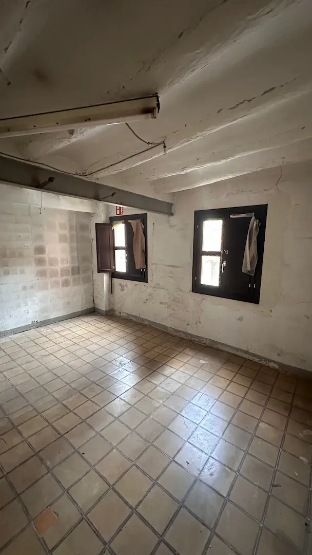 Espacio previo a la reforma en Arrabal con ventanas oscuras y techo deteriorado
