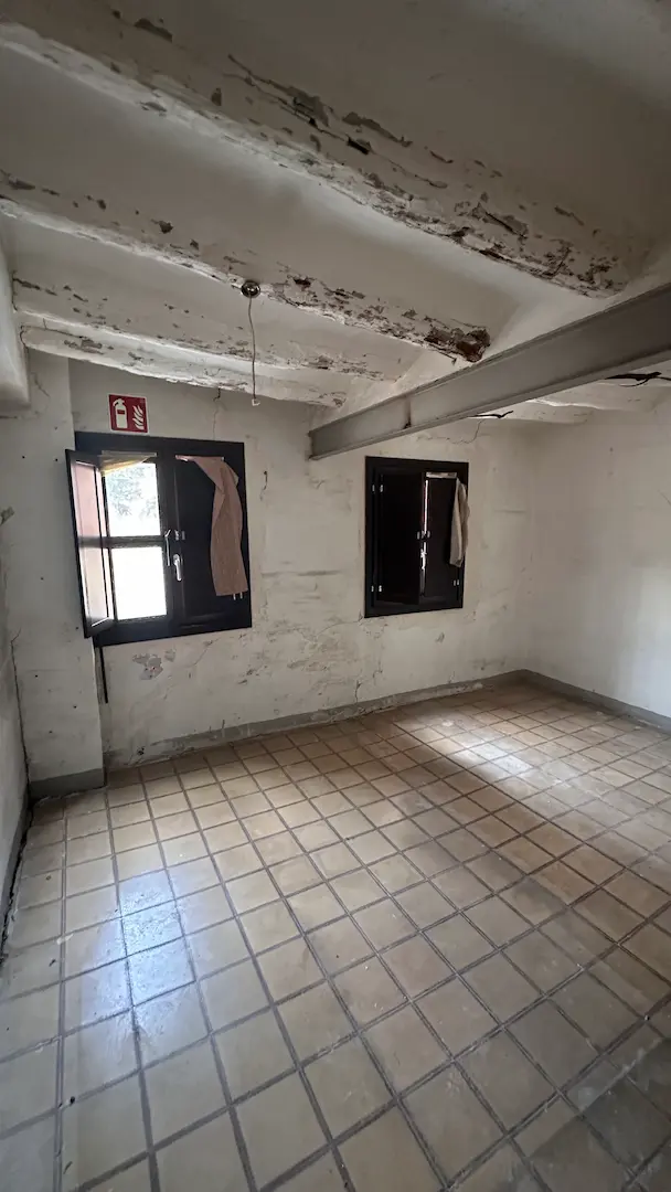 Espacio principal antes de la reforma en Arrabal con fisuras y vigas vistas