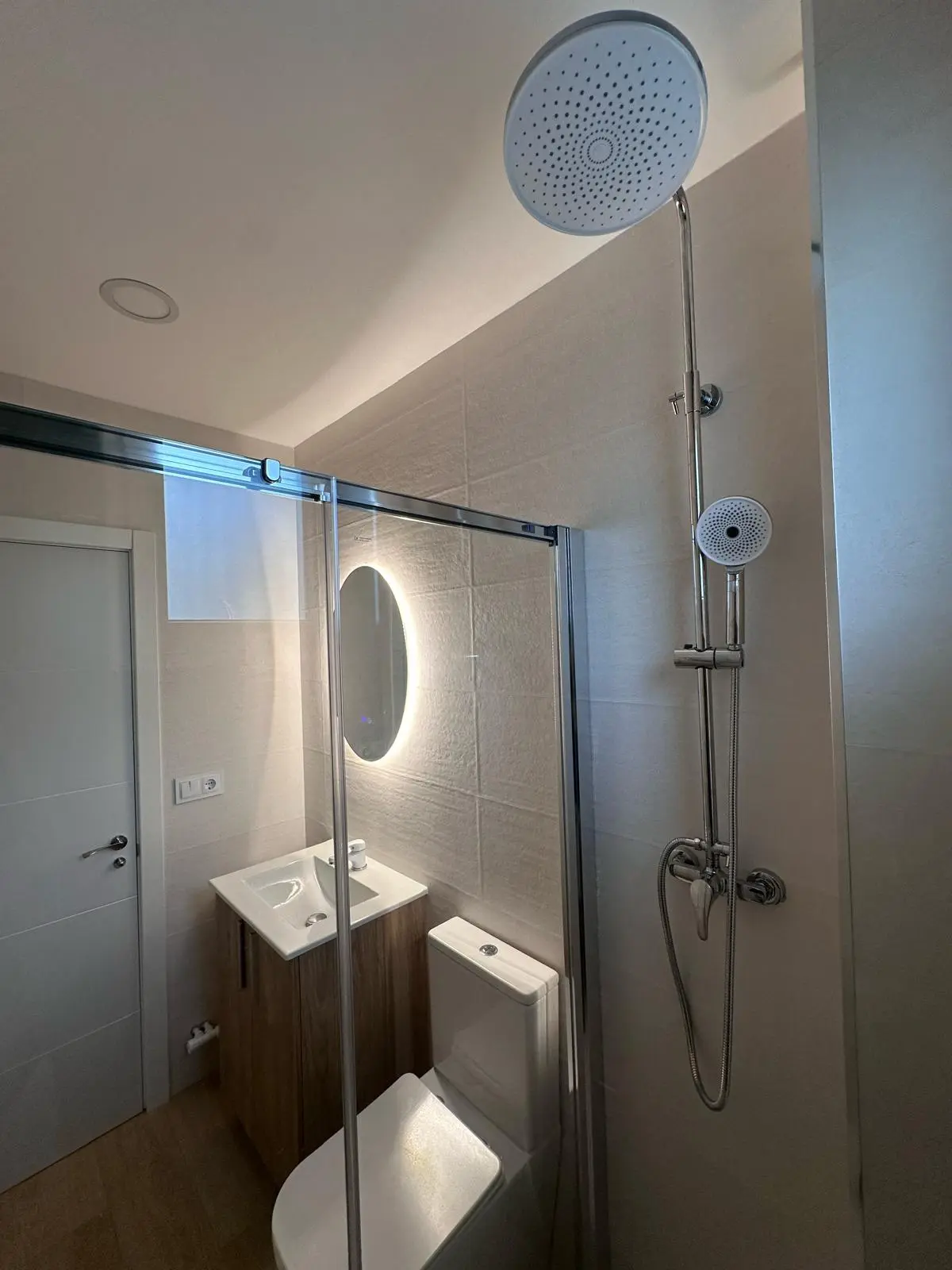 Detalle del baño reformado en Delicias con revestimientos claros y ducha