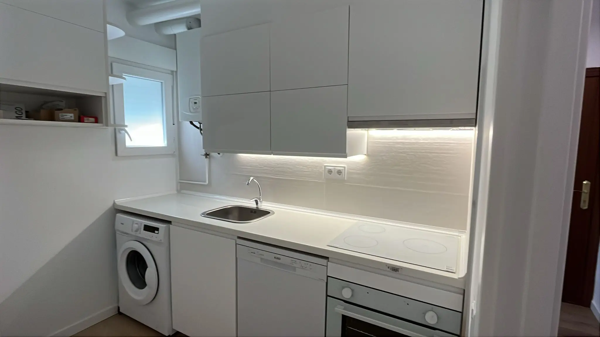 Vista de la cocina reformada en Delicias con encimera clara y mobiliario blanco
