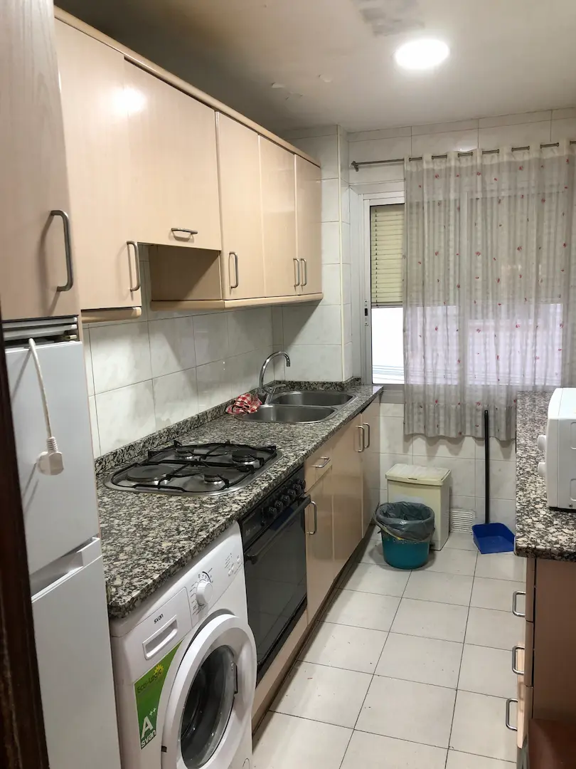 Cocina original estrecha con acabados beige y encimera de granito
